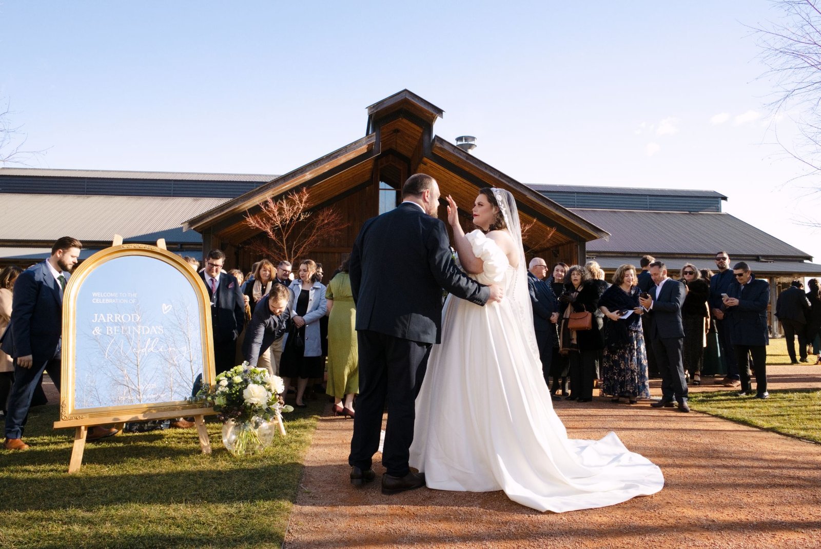 The newlyweds in front of the venue, surrounded by their guests